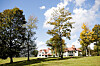 Elm Court estate building sits beyond a broad lawn and autumn trees under a partly cloudy sky.