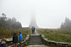 Hikers climb stone steps toward Mount Greylock’s fog-shrouded war memorial tower.